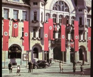 Pripadniki nemške kolesarske enote, 183. pehotna divizija, na poti proti Ptuju skozi eno od okoliških vasi, 8. april 1941. Medtem so se že začele sabotažne akcije etničnih Nemcev v Ptuju, kamor so Nemci vkorakali okrog pol treh popoldne na isti dan. Z nacističnimi zastavami okrašena mestna hiša na Ptuju aprila 1941.